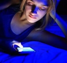 Woman alone in dark illuminated by phone screen